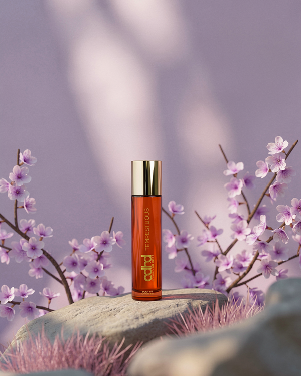 Tempestuous Body Oil 120 ml by Nadeen Al Fahad on a rock with lilac blossom branches